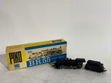 un vieux circuit de train miniature avec une boîte posée sur une surface blanche