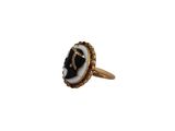 a close up of a gold ring with a black and white stone