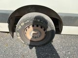 a dirty tire on the side of a white van