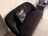 a black couch with a bag on it in the corner of a room