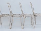 three white metal chairs sitting next to each other on a white surface
