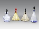 trois flacons de parfum en verre avec des bouchons noirs et un bouchon rouge