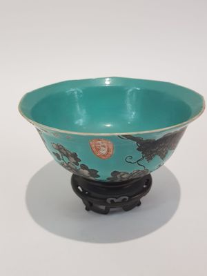 a blue bowl sitting on a black stand on a white surface