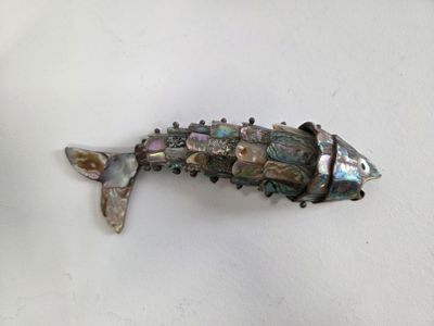 silver and abana shell fish broochle on a white surface