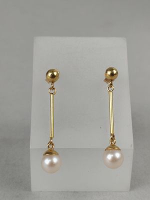 a pair of pearl and gold earrings on a white stand
