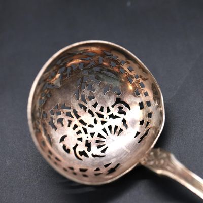 a silver spoon with a design on it on a black surface
