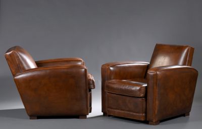 pair of brown leather club chairs on a grey background