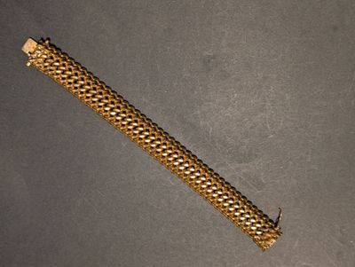 gros plan d'un bracelet en or sur une surface grise