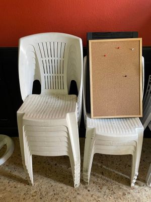 trois chaises en plastique blanc, avec un tableau en liège fixé au dossier