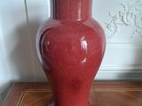 a red vase sitting on top of a wooden table