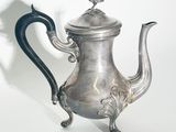 une théière en argent avec une anse noire sur fond blanc