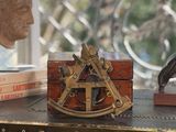 a wooden box with a brass compass on top of it