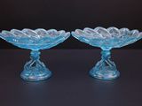 paire de plats en verre bleu reposant sur des socles, posés sur un support noir