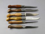 six knives are lined up in a row on a table