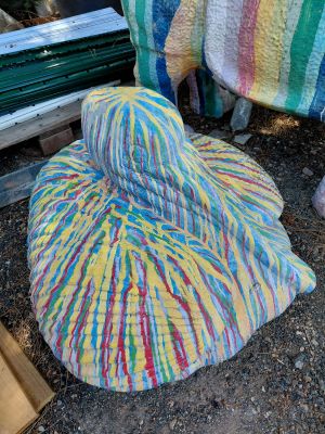 un chapeau coloré posé par terre à côté d'un tas de couvertures