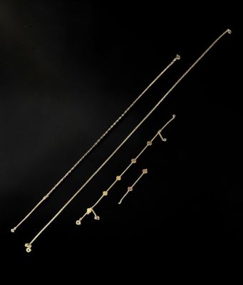 trois colliers en or ornés de flèches sur fond noir