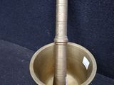 an antique brass mortar with a wooden handle on a blue background