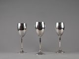 three silver wine glasses sitting next to each other on a table