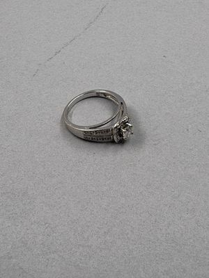 une bague en argent sertie d'un diamant, posée sur une table