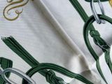 a close up of a green and white scarf with a monogram