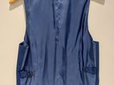 the back of a blue vest hanging on a wooden hanger