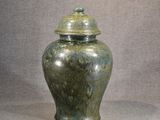a green vase with a lid sitting on a table