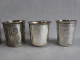 four silver cups are lined up in a row on a gray surface