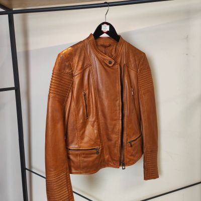 une veste en cuir marron suspendue à un porte-manteau dans une pièce