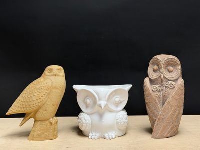 trois figurines de chouettes posées les unes à côté des autres sur une table