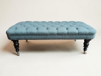 banc bleu capitonné aux pieds noirs sur fond blanc