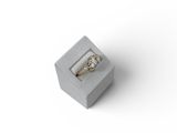 une photo d'une bague en diamant dans un écrin posé sur une surface blanche