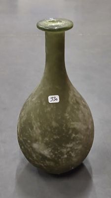 un vase vert posé sur une table, avec une étiquette dessus