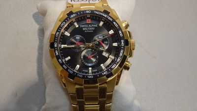 gold watch with black face and red hands on display in a store