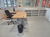 a desk with a chair and a trash can in the middle of the room