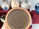 a person holding a small brown bowl with a smiley face on it