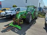 un tracteur vert garé sur un parking à côté d'un camion blanc