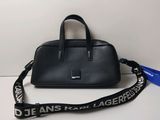 Le sac à main noir est posé sur la table, avec une lanière qui l'entoure.