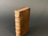 an old book sitting on top of a table next to a gray wall