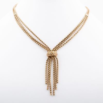 a gold necklace with a chain and a tassel on a mannequin mannequin