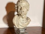une statue représentant un homme barbu posée sur une table en bois