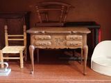 une maison de poupées dans laquelle se trouvent un bureau et des chaises