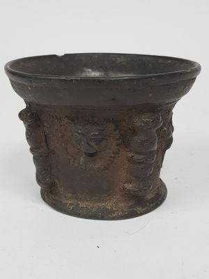 un vieux vase en bronze orné d'un motif représentant un visage