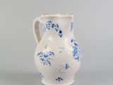 blue and white vase with flowers on it sitting on a gray surface