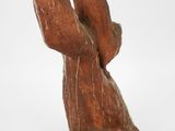 statue of a person holding a piece of wood on a white surface