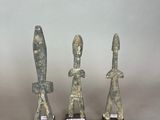 three stone statues of a man and a woman on a table
