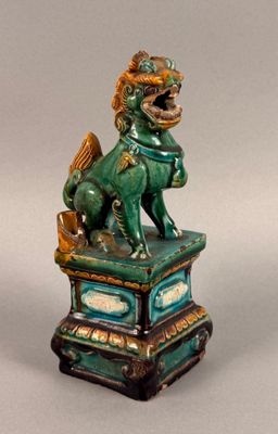 statue of a lion on a pedestal with a basket in its mouth