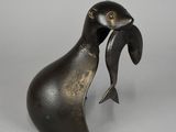 une statue en bronze représentant un oiseau tenant un poisson dans son bec