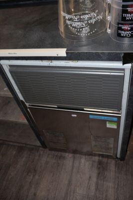 a small refrigerator that has a bucket on top of it