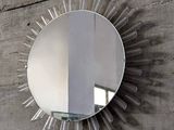 un miroir accroché au mur, orné d'un motif en rayons de soleil