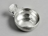 une cuillère en argent posée sur une table, avec une pièce à l'intérieur